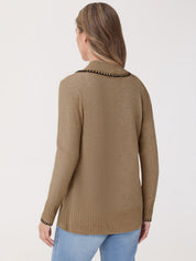 Woman wearing a beige sweater with decorative trim on a white background