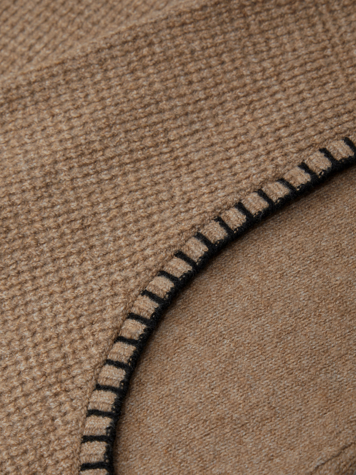 Close-up of a brown fabric with a black-stitched edge