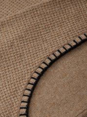 Close-up of a brown fabric with a black-stitched edge