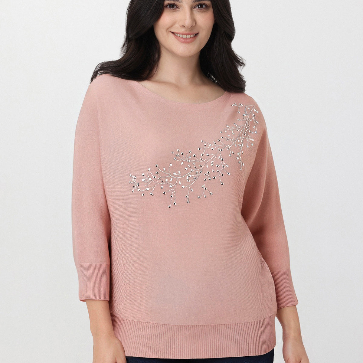 Woman wearing a pink sweater with decorative elements on a white background