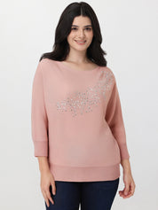 Woman wearing a pink sweater with decorative elements on a white background