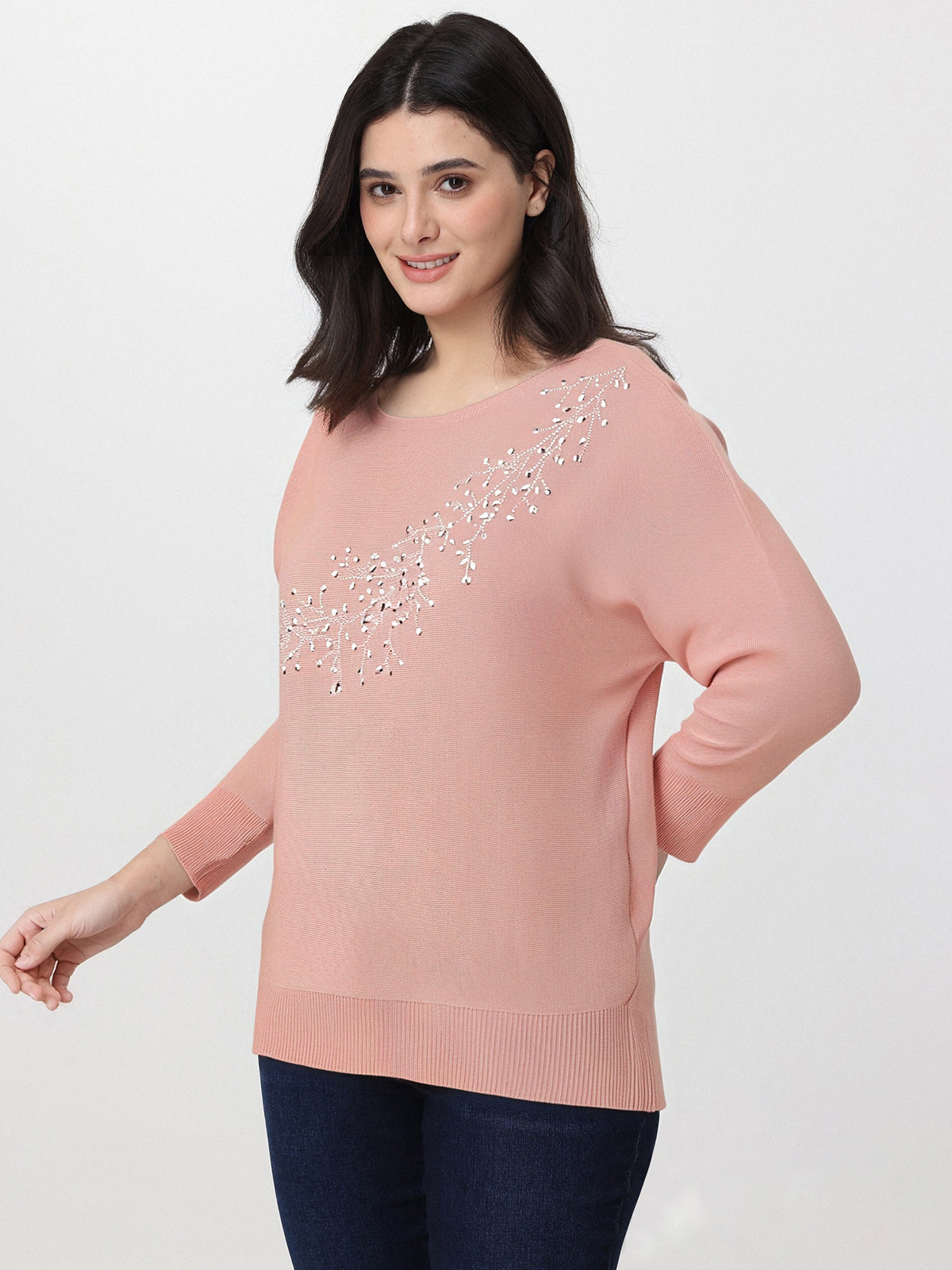 Woman wearing a pink sweater with decorative elements on a white background