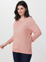Woman wearing a pink sweater with decorative elements on a white background