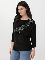 Woman wearing a black top with rhinestone embellishments on a white background