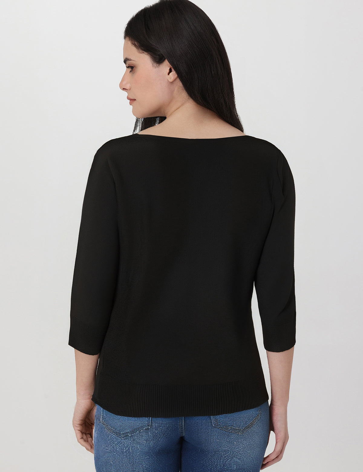 Woman wearing a black top and blue jeans on a white background