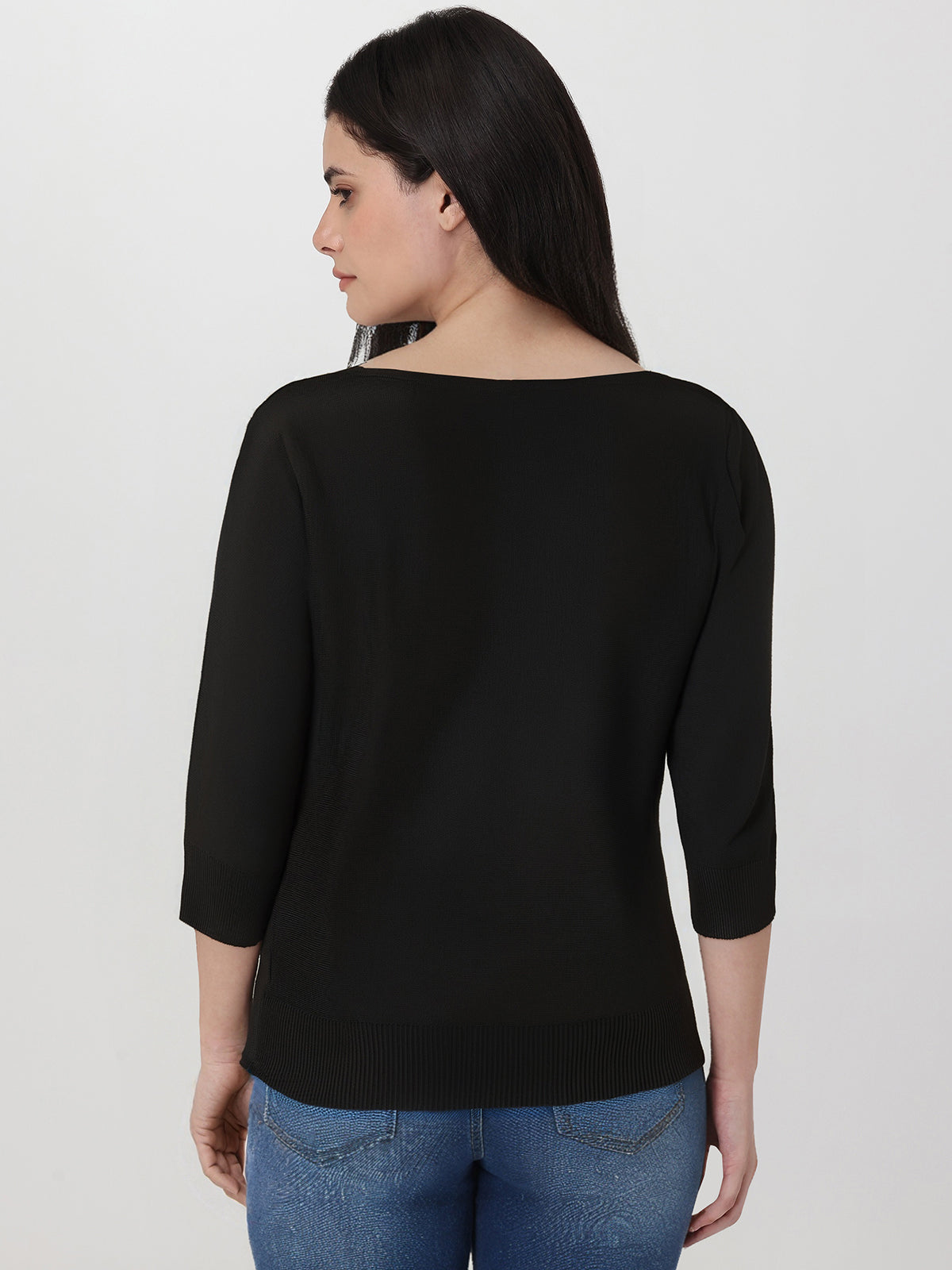 Woman wearing a black top and blue jeans on a white background