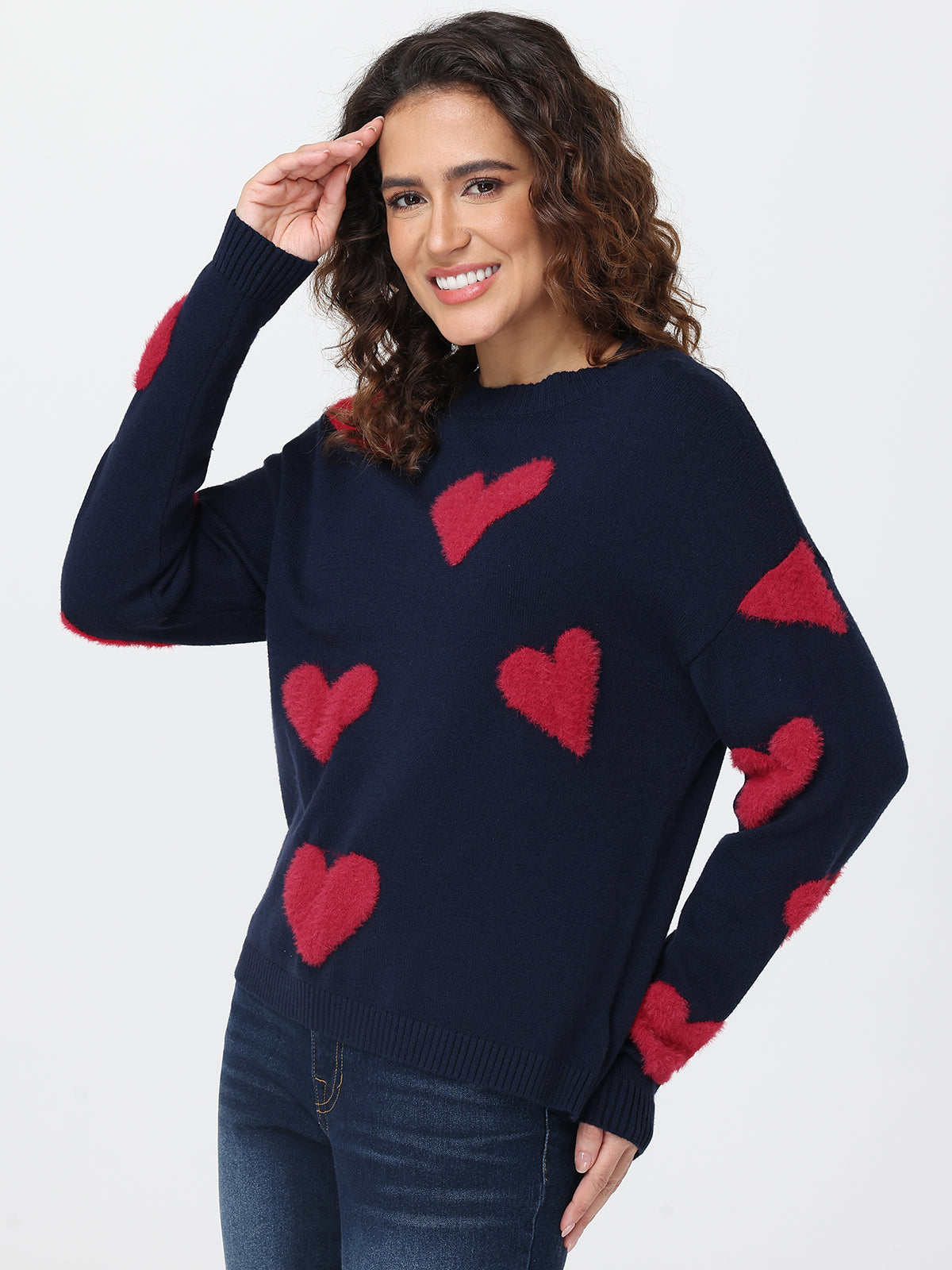 Woman wearing a navy sweater with red heart patterns on a white background
