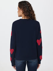 Navy sweater with red heart patterns on a plain background