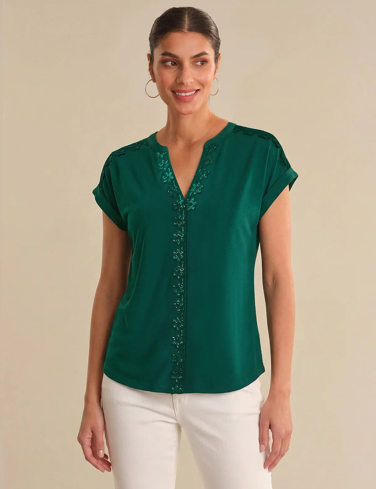 Woman wearing a green blouse with embroidery on a beige background