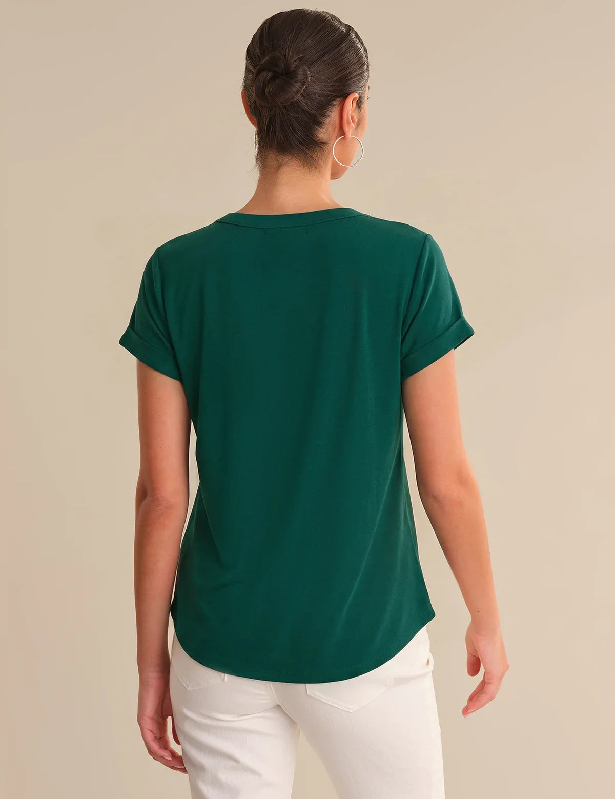 Person wearing a green t-shirt and white pants on a beige background