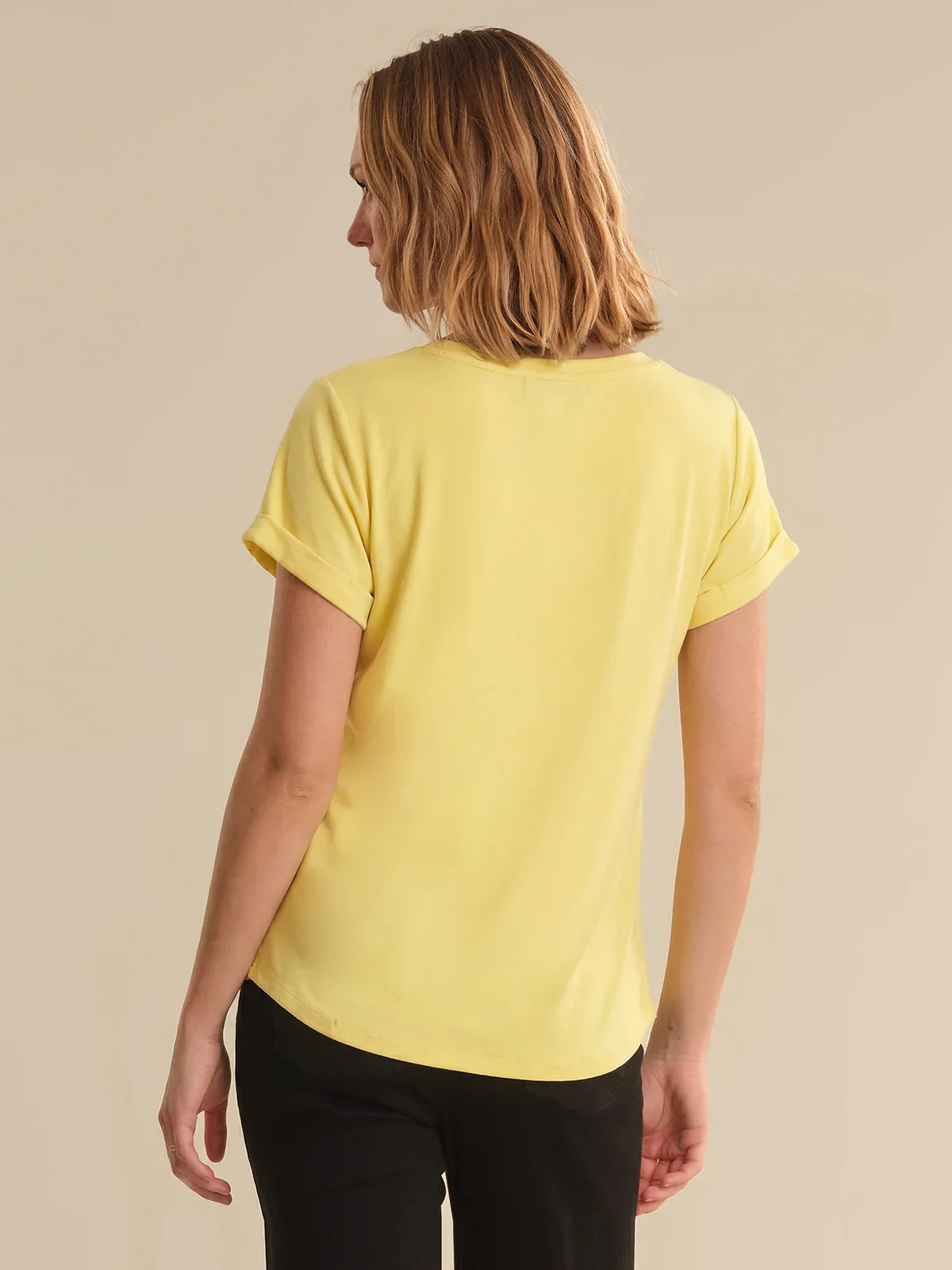 Person wearing a yellow t-shirt on a beige background