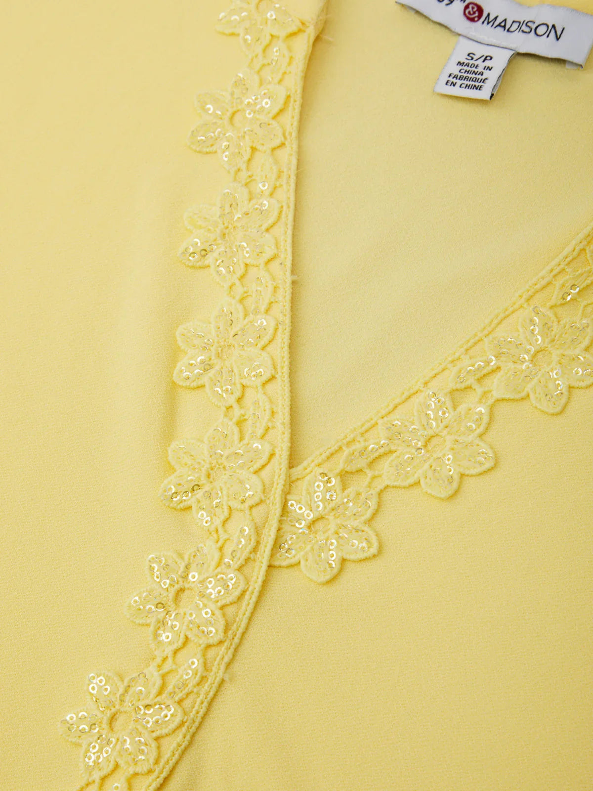 Yellow garment with floral lace trim and a visible label.