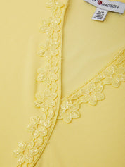 Yellow garment with floral lace trim and a visible label.