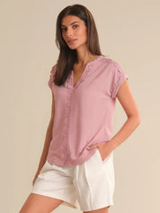 Woman wearing a pink blouse with lace details on a beige background