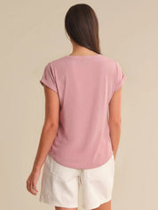 Woman wearing a pink t-shirt and white shorts on a beige background