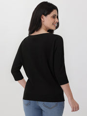 Woman wearing a black top and blue jeans on a white background