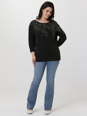 Woman wearing a black embellished top and blue jeans on a white background
