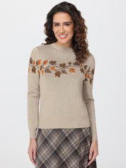 Woman wearing a beige sweater with leaf pattern and plaid skirt on a white background