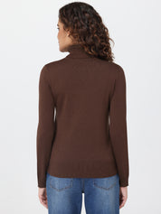 Woman wearing a brown turtleneck sweater and blue jeans on a white background