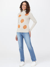 Woman wearing a cream sweater with orange patterns and blue jeans on a white background
