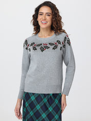 Woman wearing a gray sweater with floral patterns on a white background