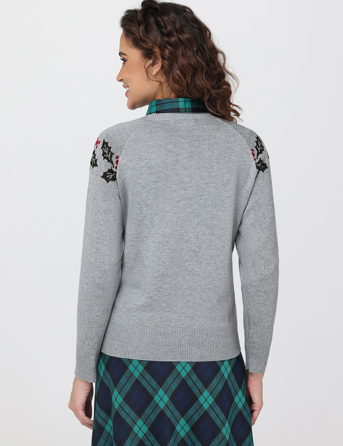 Woman wearing a gray sweater with floral embroidery on a white background