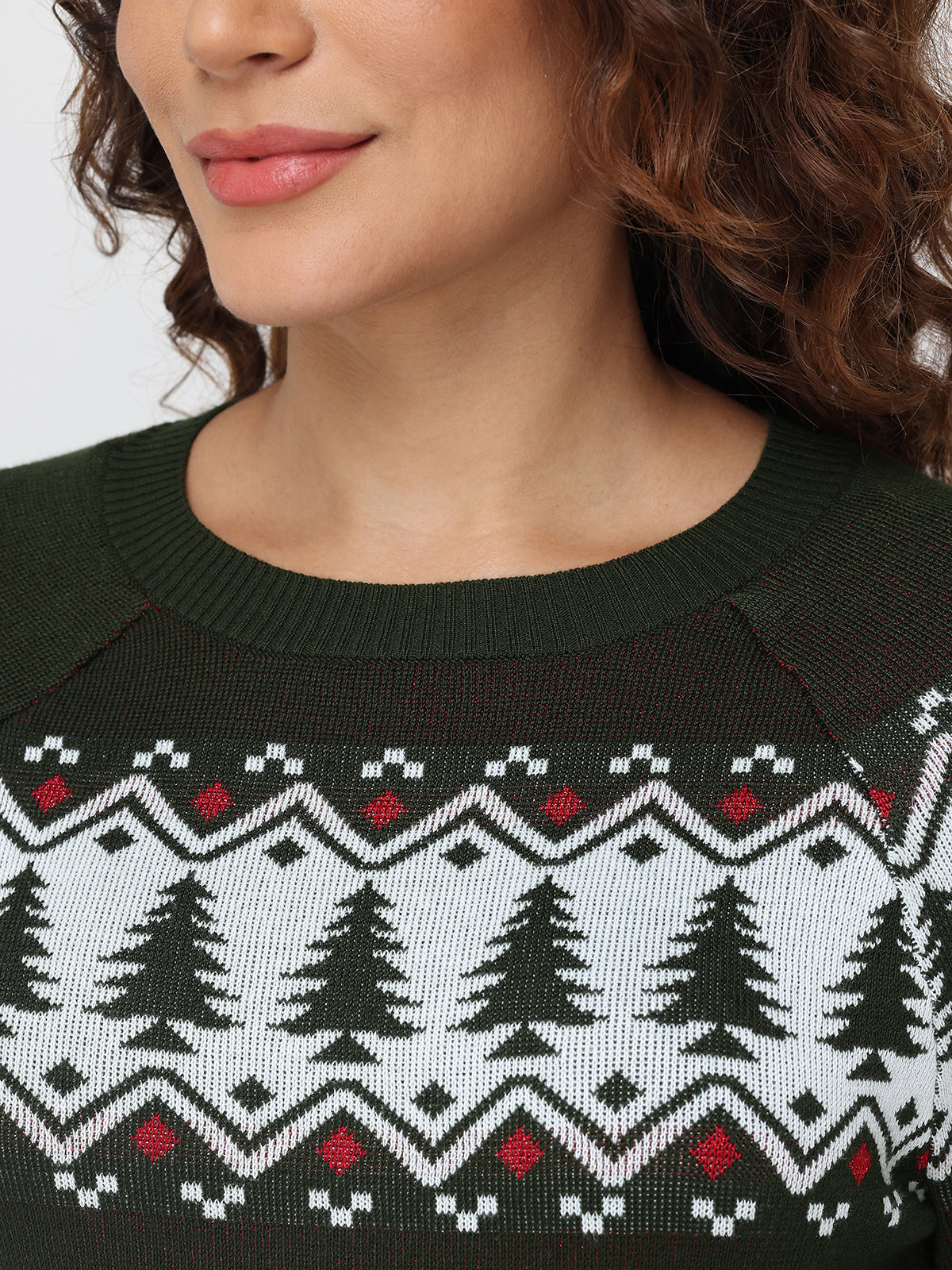 Close-up of a person wearing a sweater with a Christmas tree pattern.