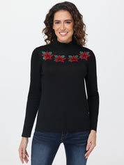 Woman wearing a black turtleneck sweater with red and green floral patterns on a white background