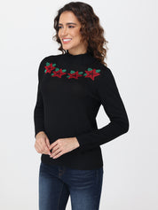 Woman wearing a black sweater with red and green floral embroidery on a white background