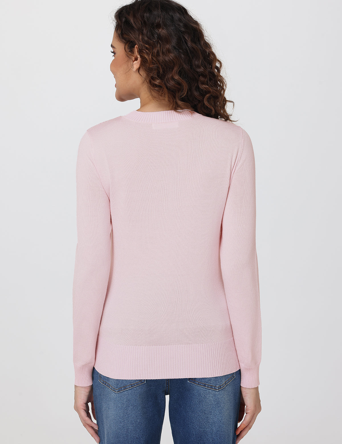 Woman wearing a light pink sweater and blue jeans on a white background