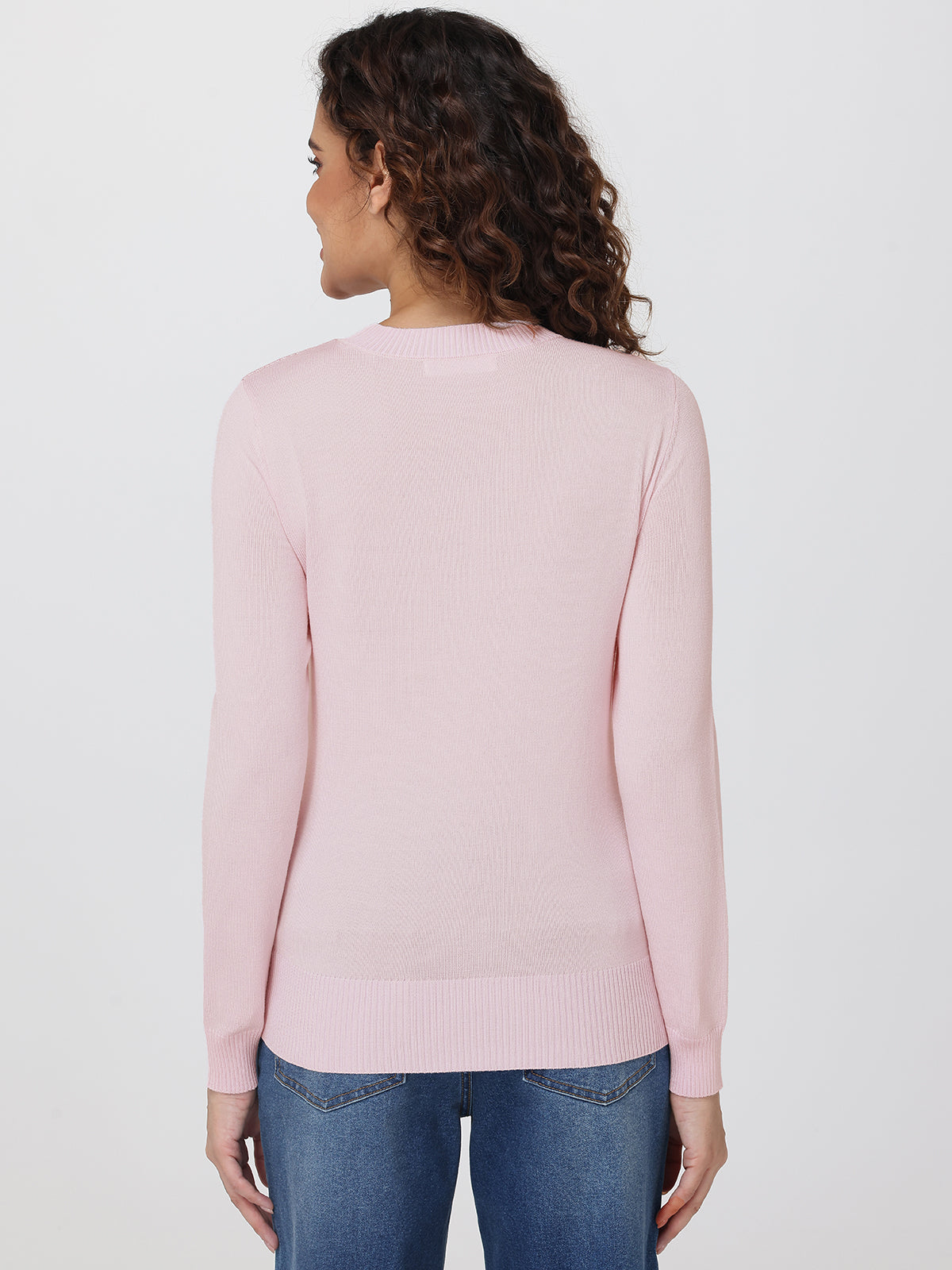 Woman wearing a light pink sweater and blue jeans on a white background