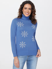 Woman wearing a blue sweater with snowflake patterns on a plain background