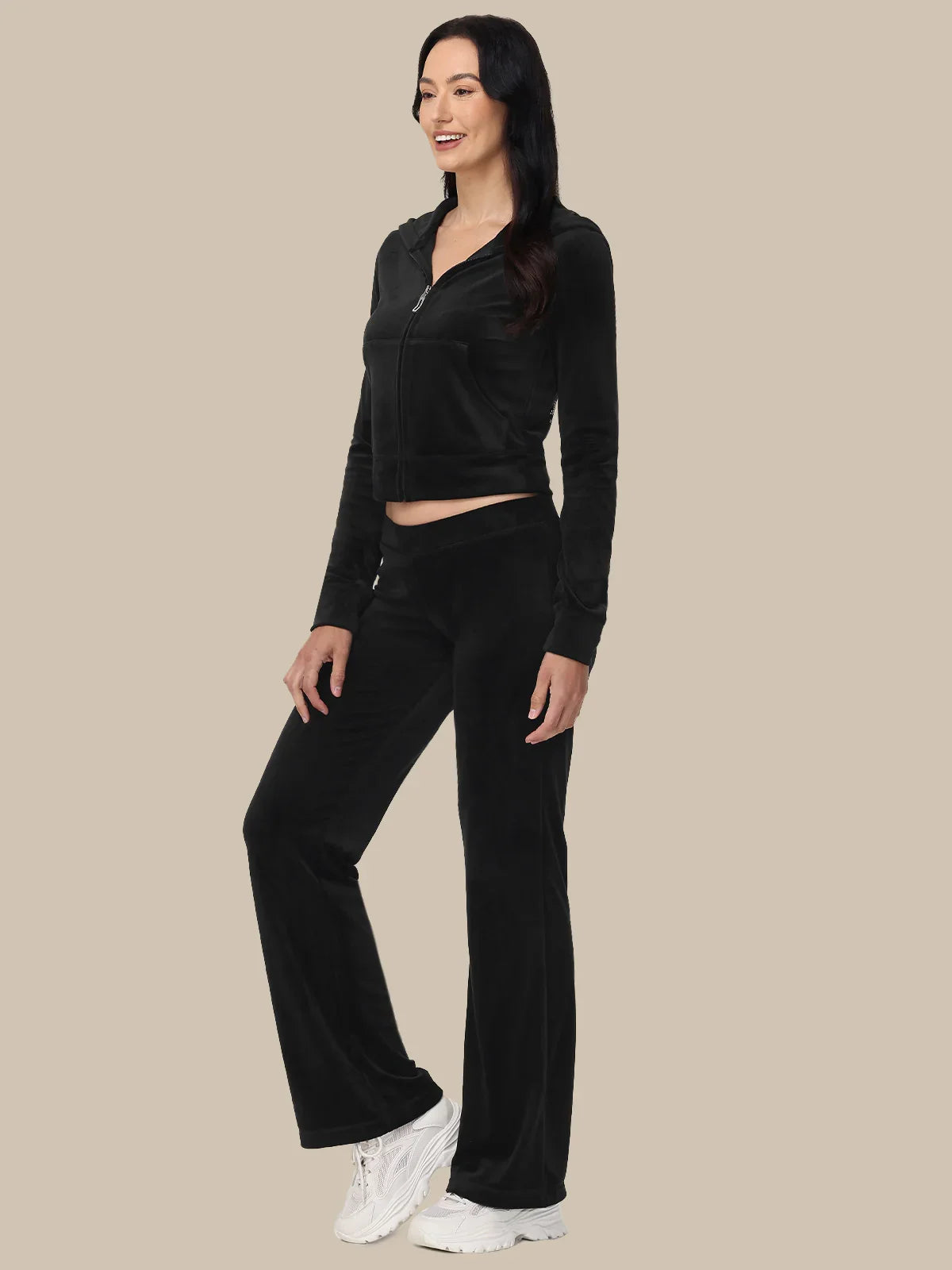 Woman wearing a black long-sleeve top and black pants on a beige background