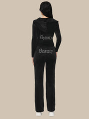 Black tracksuit with 'Beauty' text on the back worn by a person against a beige background