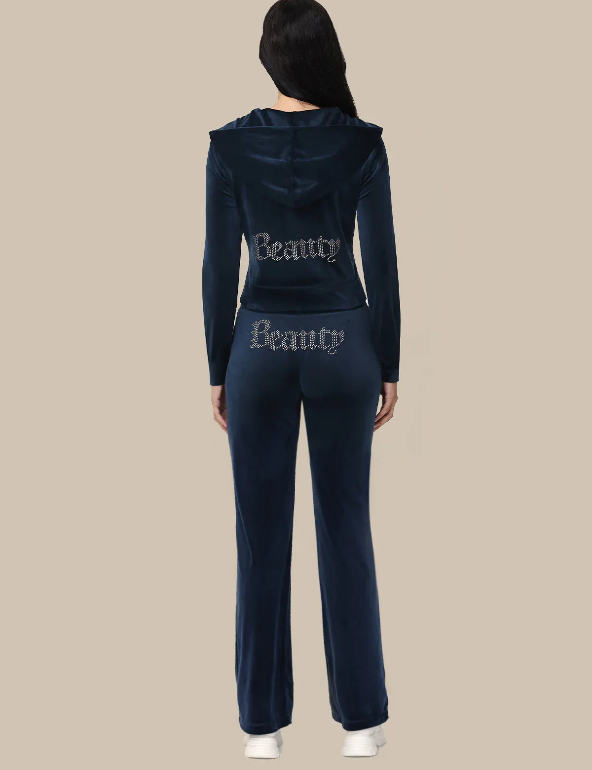 Person wearing a navy tracksuit with 'Beauty' text on a beige background