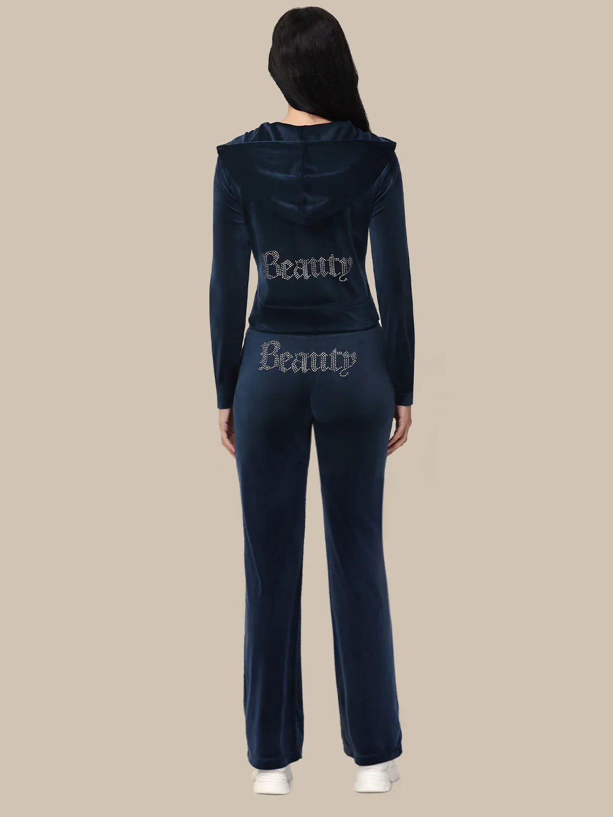 Person wearing a navy tracksuit with 'Beauty' text on a beige background