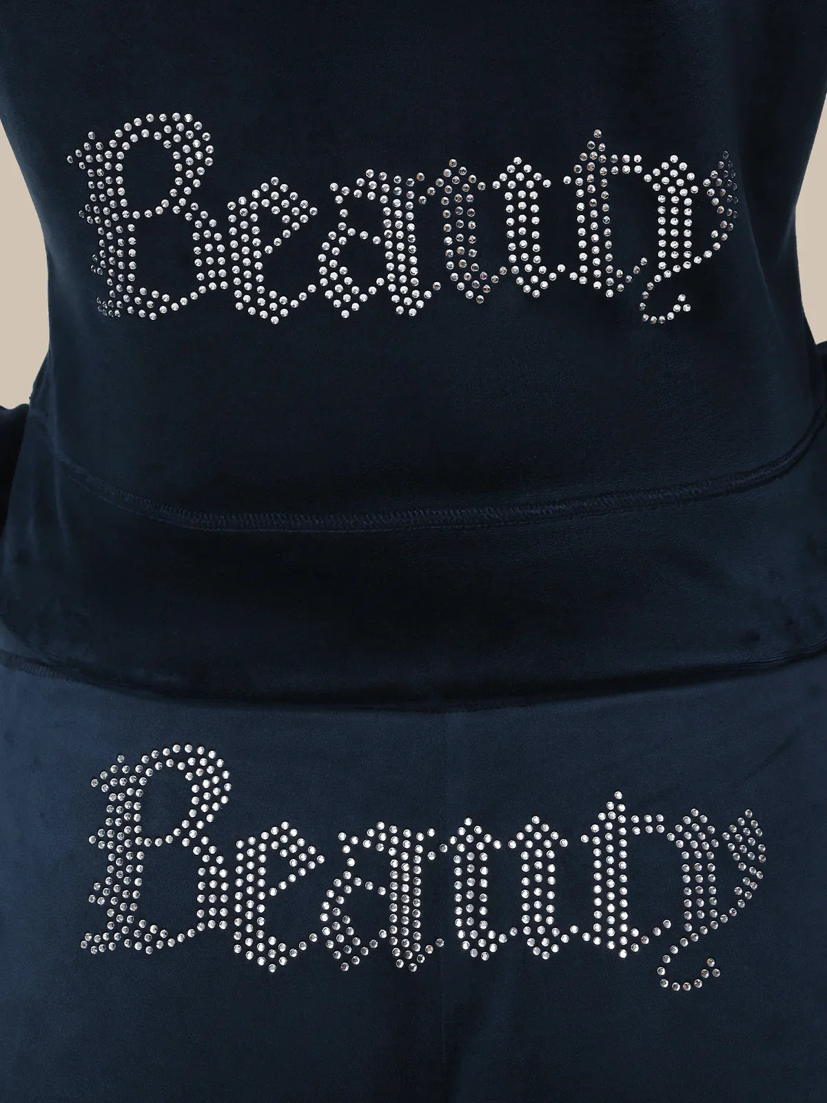 Black hoodie with 'Beauty' text in rhinestones on a beige background