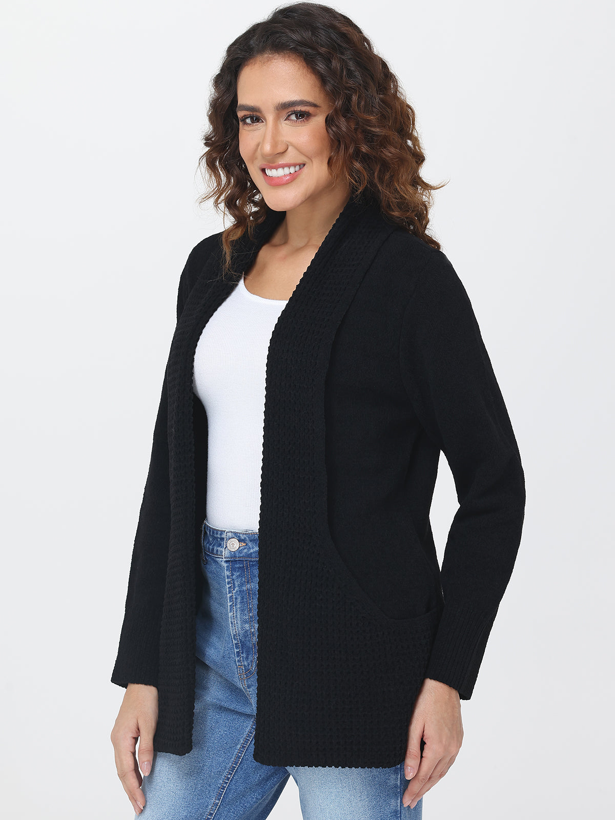 Woman wearing a black cardigan over a white shirt and blue jeans on a white background