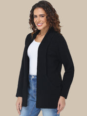 Woman wearing a black cardigan over a white shirt and blue jeans on a beige background