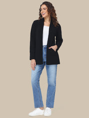 Woman wearing a black blazer, white shirt, blue jeans, and white sneakers on a beige background