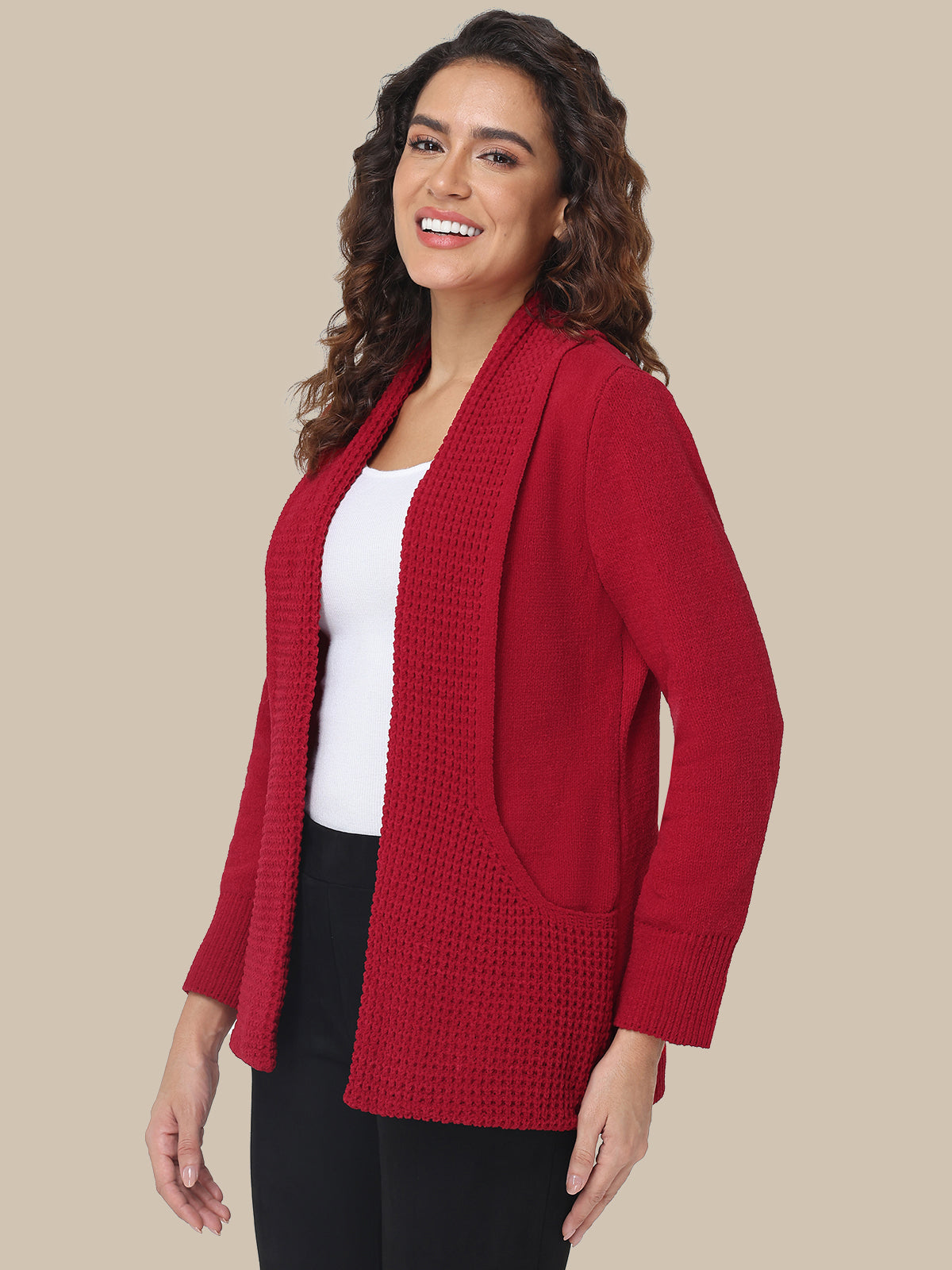 Woman wearing a red cardigan over a white top and black pants on a beige background