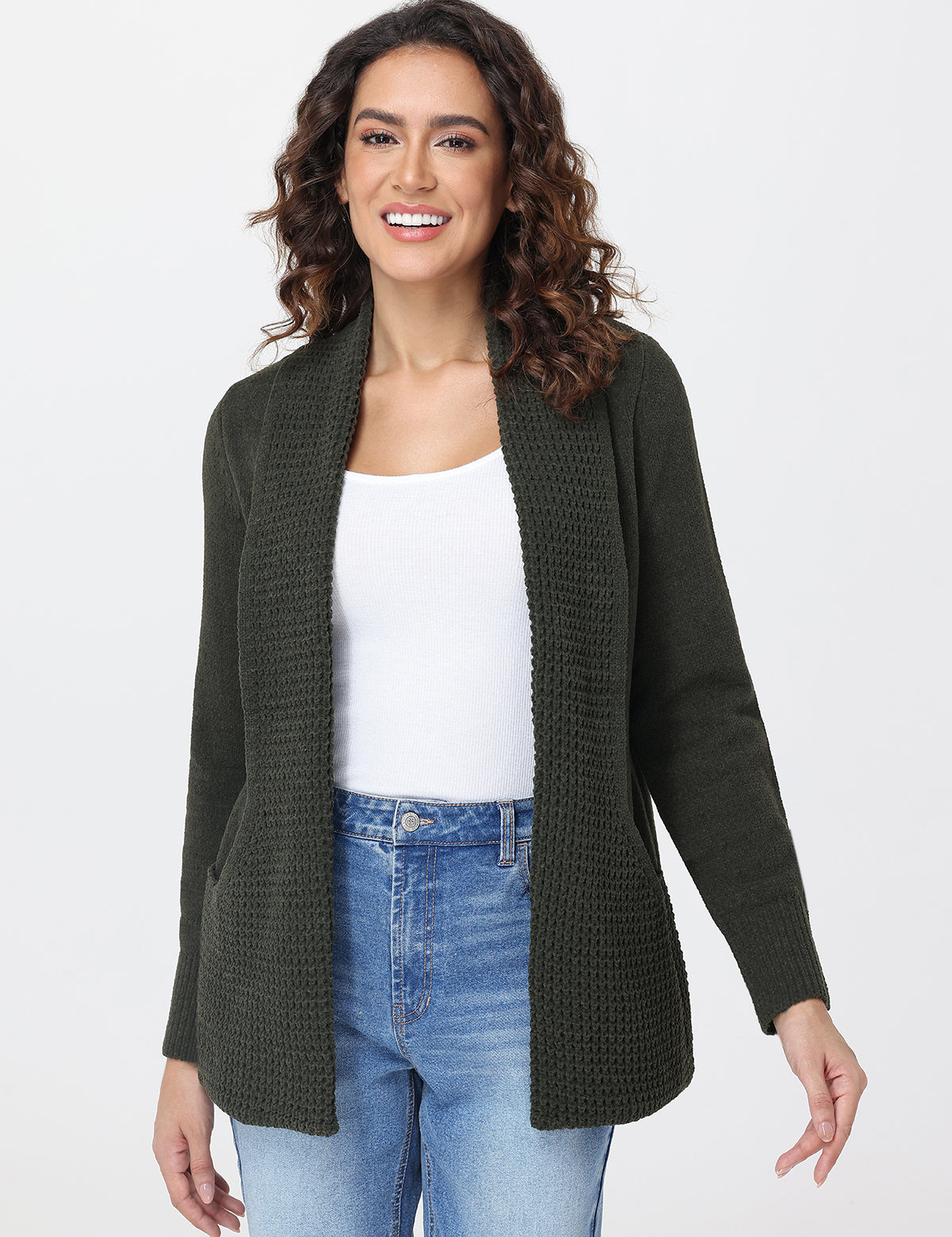 Woman wearing a green cardigan over a white top and blue jeans on a white background