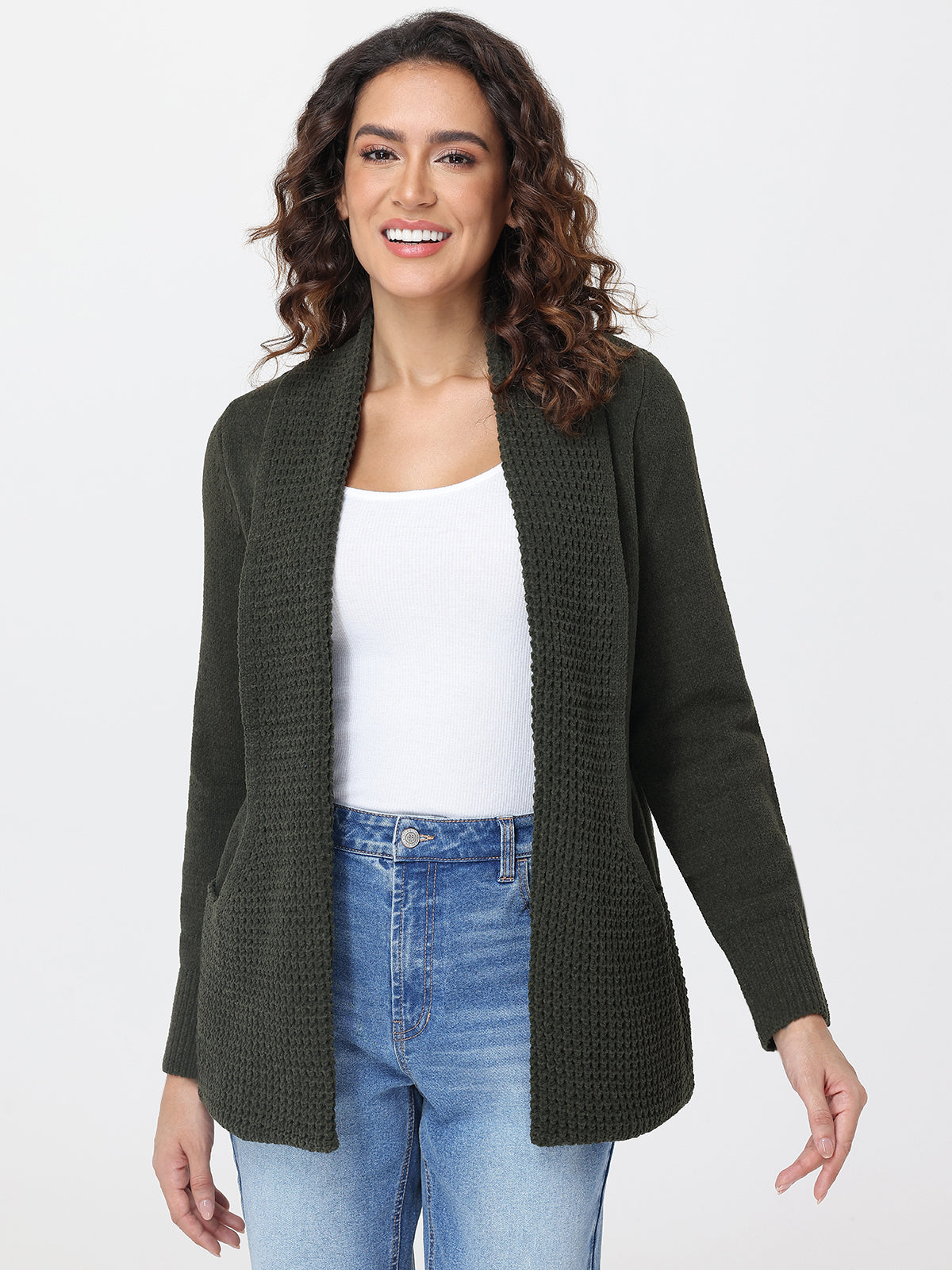 Woman wearing a green cardigan over a white top and blue jeans on a white background