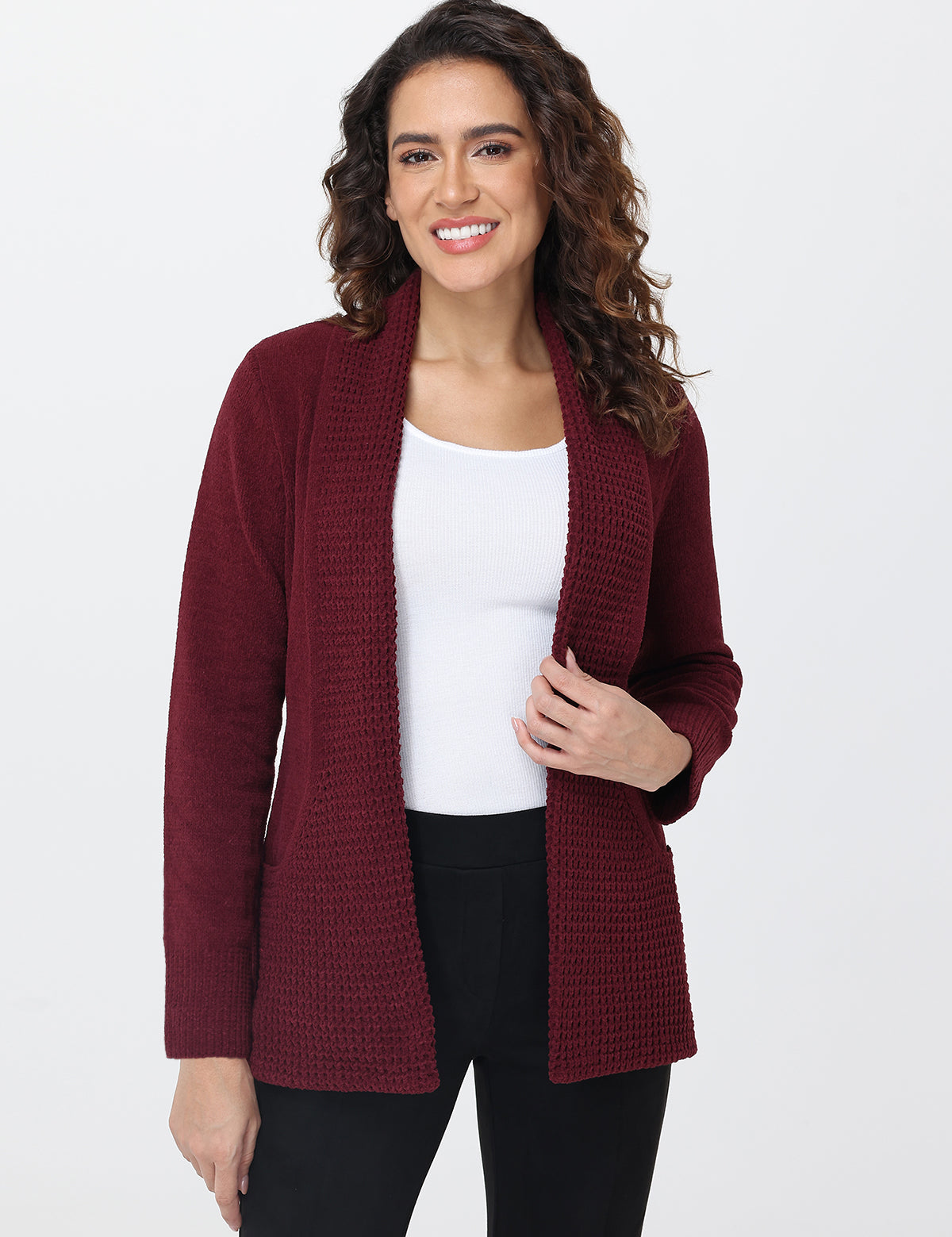 Woman wearing a burgundy cardigan over a white top and black pants on a white background