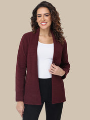 Woman wearing a burgundy cardigan over a white top and black pants on a beige background