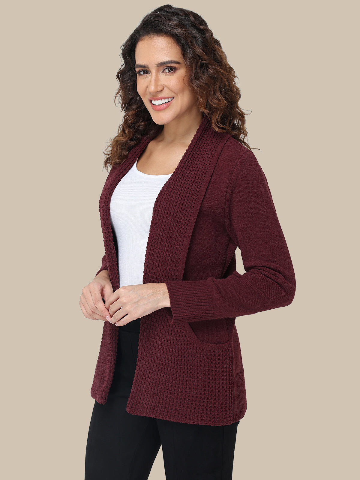 Woman wearing a burgundy cardigan over a white shirt on a beige background