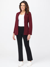 Woman wearing a burgundy cardigan, white top, black pants, and white shoes on a white background