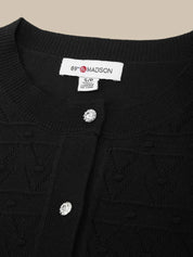 Black cardigan with a brand label on a beige background