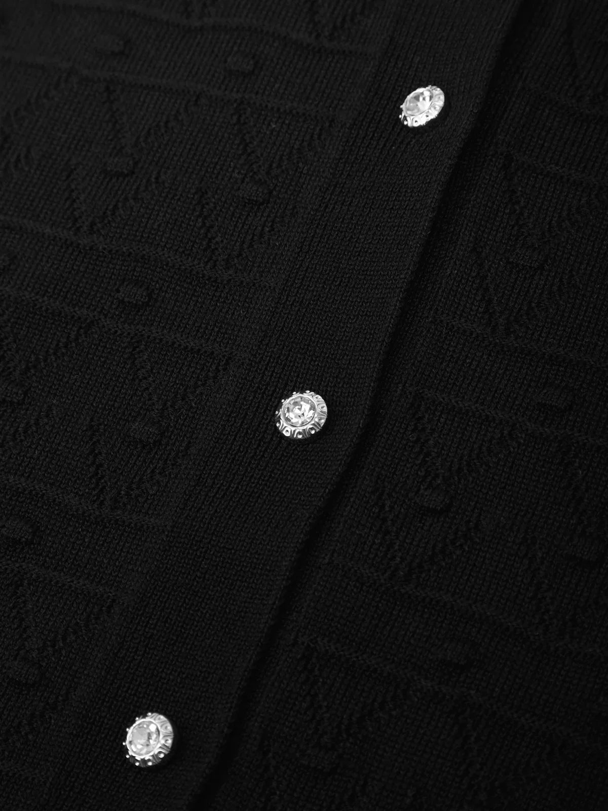 Close-up of a black textured fabric with silver buttons.