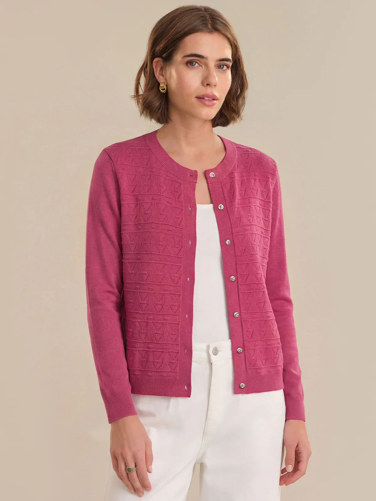 Woman wearing a pink cardigan over a white top on a beige background
